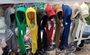 Multiple colors of knitted hood scarves on a metal rack showing fabric texture