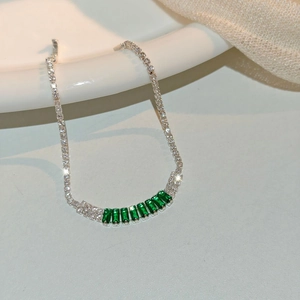 Macro shot of silver chain bracelet with rectangular emerald stones and white zirconia