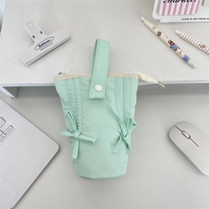 Close-up of mint green quilted stationery bag with bow detail and zipper closure