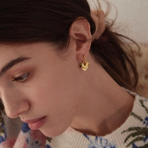 Close-up of model wearing heart-shaped 18k gold plated hoop earrings in a minimalist style