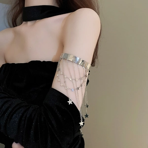 Silver armlet detail featuring shimmering star fringe pendants on a wide metallic band