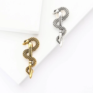Detail of snake-shaped metal pins in gold and silver finish with textured skin pattern