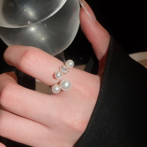 Close-up of elegant gold ring with pearls and a sparkling central zircon on finger