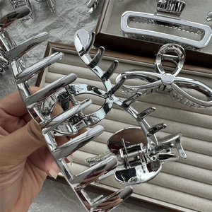 Close-up of silver metal shark hair clips in antler and bow shapes on a velvet tray