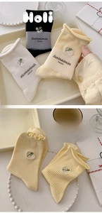 Detail of floral embroidery on cotton socks with scalloped edges in cream and black