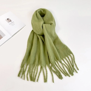 Close-up of soft avocado green mohair scarf with fringe details and fluffy texture