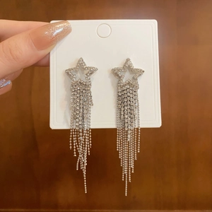Detail of silver tassel earrings with star design and sparkling rhinestones on card