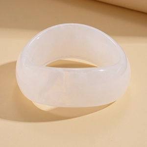 Close-up of translucent white acrylic bangle with cloudy marble texture and geometric design