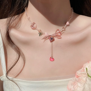 Detailed view of sweet pink beaded heart necklace with bow pendant on a model's neck