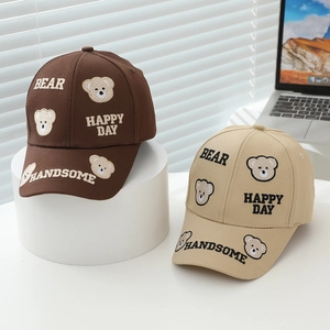 Detailed close-up of brown and beige kids baseball caps with teddy bear embroidery