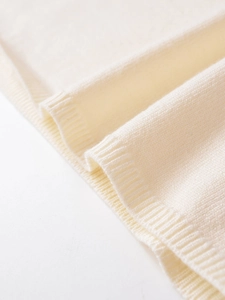 Macro detail of beige wool blend knitwear showing fine texture and ribbed edge craftsmanship