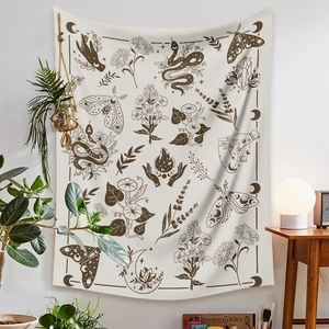 Detail of bohemian tapestry featuring snake, moon, and moth graphics on beige fabric