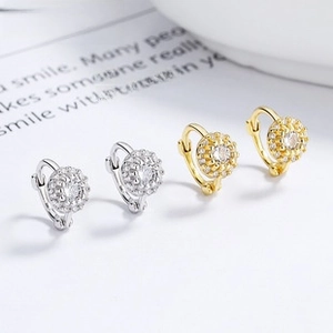 Detail of silver and gold round pavé hoop earrings with radiant cubic zirconia charms