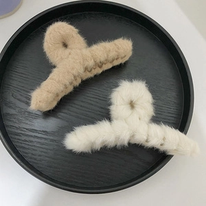 Detail of plush faux fur hair claws in khaki and cream on a decorative wooden tray