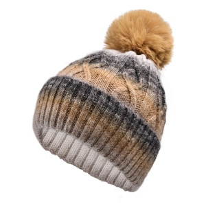 Close-up of cable knit beanie texture with a large fluffy faux fur pompom on top