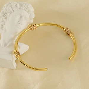 Close-up of golden vintage-style C-shaped open bangle with twisted wire details