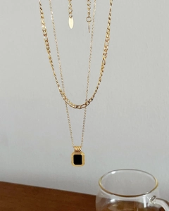 Detail of a vintage double-layered 18k gold-plated necklace with a black square pendant