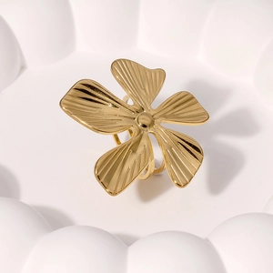 Bague fleur dorée polie avec textures radiales dans un décor floral épuré