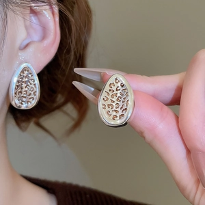 Detailed view of leaf-shaped leopard print earrings with polished silver metal edges