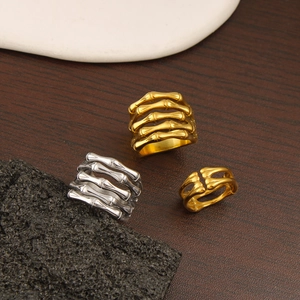 Detailed view of geometric bone-shaped rings in 18K gold and silver finishes on stone