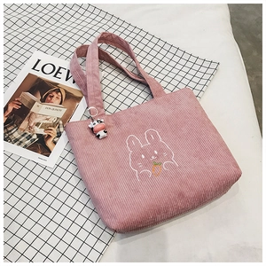 Pink corduroy tote bag detail with rabbit embroidery and a cute cow plush keychain