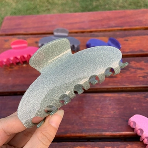 Close-up of silver glitter acetate hair claw clip with seven teeth in natural light