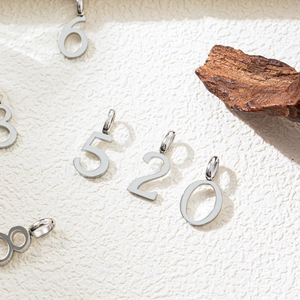Polished silver number charms 5206 made of stainless steel on a rustic wood background