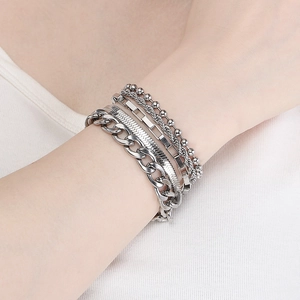 Close-up of layered silver stainless steel bracelets featuring snake and cuban link chains