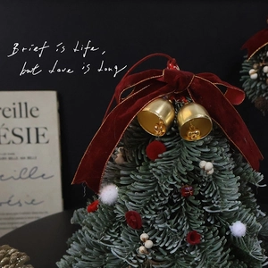 Mini artificial Christmas tree with red velvet bow and golden bells for festive decor