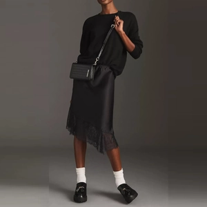 Detailed look at a black silk skirt with delicate lace trim and matching loafers
