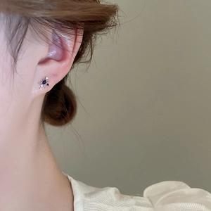 Detail of silver stud earring featuring deep blue oval zircon and sparkling starburst accents