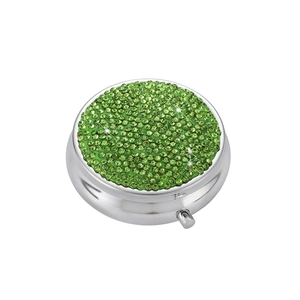 Detail of round silver pill box with green rhinestones and push-button closure