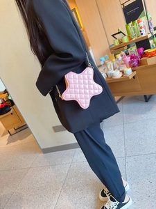 Detailed view of pink star-shaped quilted bag with elegant gold chain strap on a model