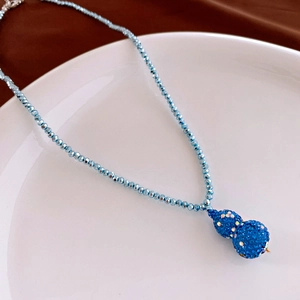 Macro shot of a sparkling blue rhinestone-studded gourd pendant on a beaded necklace