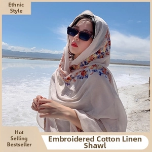 Close-up of beige linen ethnic shawl with colorful embroidery against a blue sky