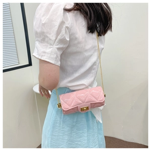Detail of pink quilted cylindrical jelly bag with gold chain strap on a female model