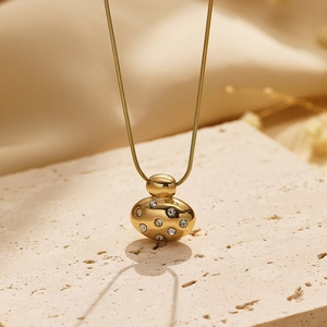Gold oval pendant necklace with sparkling zircons on elegant stone surface
