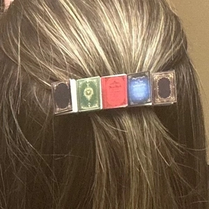 Detail of miniature vintage book hair clip featuring colorful covers on female hair