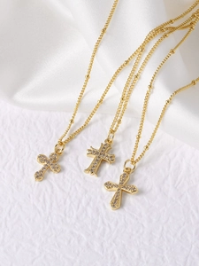 Detailed close-up of three 18k gold plated cross necklaces with sparkling zircon inlay