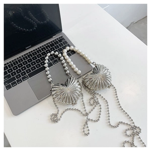 Close-up of heart-shaped silver metal evening bags with pearl handles and beaded chains