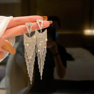 Macro detail of silver tassel earrings with geometric triangle and crystal fringe