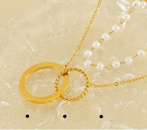 Détail macro du collier doré à deux rangs avec anneaux en acier inoxydable et perles