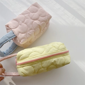 Detailed view of quilted floral makeup bags in pink and yellow with sturdy handles
