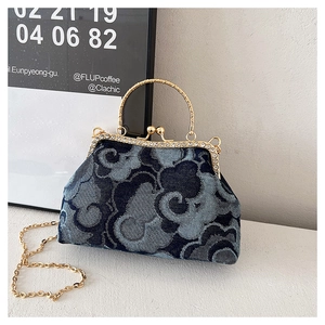 Detail of denim kiss-lock bag showing lucky cloud jacquard and rhinestone metal frame