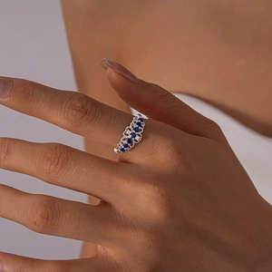 Close-up of vintage hollow silver ring with blue zircons and white crystals on finger