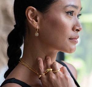 Close-up of elegant gold jewelry set featuring layered necklaces and chunky irregular rings