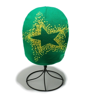 Detail of green knitted beanie featuring a yellow pixelated star on a display stand