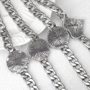 Back view of vintage silver Cuban chain bracelets with heart and round textured pendants