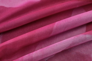 Detailansicht aus rosenrotem Mesh-Gewebe mit atmungsaktiver Stricktextur-Struktur