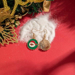 Detail of colorful Santa Claus earrings on a snowy background with festive holiday decor